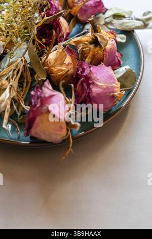 Dried flowers lie as a colorful flower arrangement on a blue-green plate Stock Photo