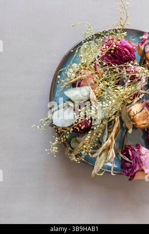 Dried flowers lie as a colorful flower arrangement on a blue-green plate Stock Photo