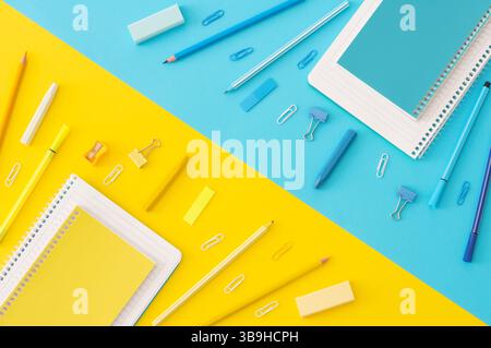 Back to school concept, school supplies and accessories on yellow and blue background, notebook, pencils, paperclip, duster, flat lay copy space Stock Photo