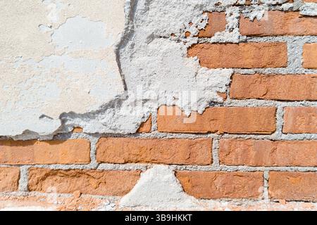 Exposed red brick wall with crumbling plaster Stock Photo