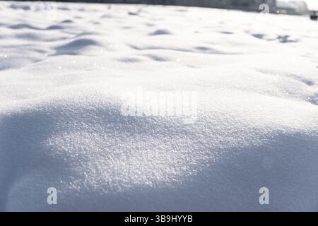 Textured snow mounds sparkling in daylight, forming natural curves and subtle shadow play. Clean, untouched surface evokes calmness and purity of wint Stock Photo
