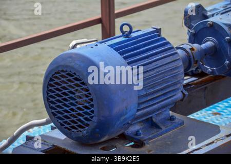 The blue motor of the water pump on the river, close-up. Water pump in a industrial building. Electric motor Stock Photo