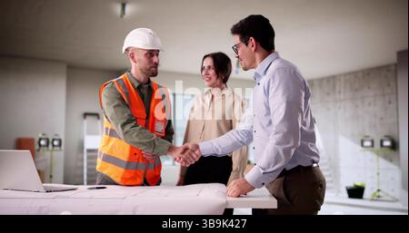Architect And Engineer Discuss Blueprint Renovation With Young Couple Stock Photo