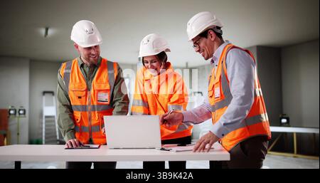 Professional Engineers Examine House Blueprint With Young Couple Looking On. Builders, Engineers Stock Photo