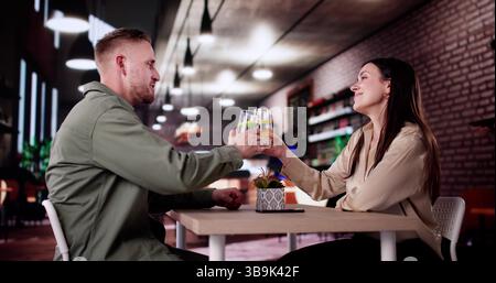 Couple Enjoying Wine And Dining At Romantic Evening Dinner Date Stock Photo