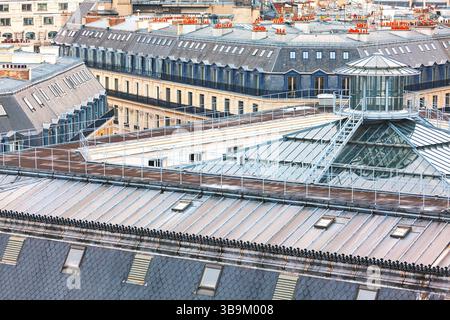 Aerial view of classic Parisian rooftops with slate tiles, dormer windows, and red chimney pots. Geometric rooftop structure adds architectural Stock Photo