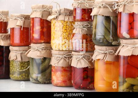 Many jars with different pickled products on light table Stock Photo