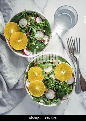 Vegan salad bowl with oranges, spinach, arugula, radish, nut. Top view. Vegan breakfast, vegetarian food, diet concept. Two bowls with salad on white Stock Photo