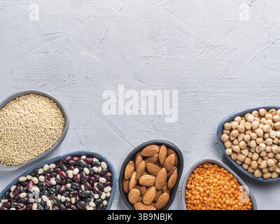 Vegetarian healthy protein sources on gray concrete background. Quinoa, chickpea, almond, red lentils, mixed bean as vegan sources of protein concept. Stock Photo