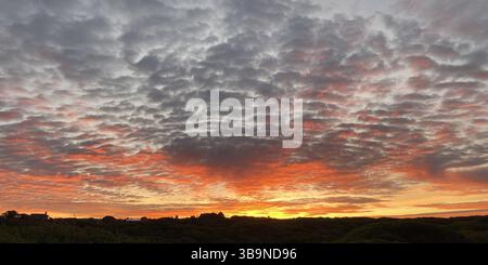 @Broken clouds into the Sunset. A dramatic Essex sunset breaking through scattered clouds, were beams of golden light pierced the sky and danced across the horizon. The layered clouds added depth and texture, turning an ordinary evening into a moment of quiet awe. Stock Photo