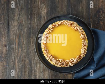 Lemon tart or lemon cake decorated chopped walnuts. Delicious whole lemon pie on wooden background. Aesthetic of traditional classic french lemon tart Stock Photo