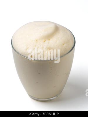 Vanilla milkshake with foam isolated on white. Delicious milk dessert with vanilla in glass isolated on white with clipping path Stock Photo