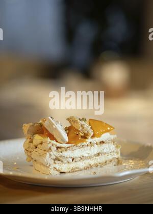 Puff layered cake with cream of cream-cheese, decorated fresh persimmons. Delicious and eye-catching piece of layered cake decorated orange persimmons Stock Photo