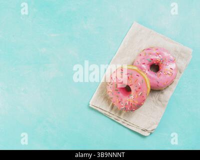 Top view of two pink donuts on blue concrete background with copy space. Colorful donuts with copyspace. Glazed doughnuts with sprinkles Stock Photo