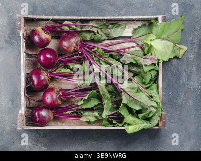 Beet, beetroot bunch in wooden box on dark stone or concrete background. Fresh ripe beetroot with leaf on dark table.. Top view or flat lay Stock Photo