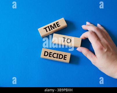 Time to decide symbol. Concept words Time to decide on wooden blocks. Beautiful blue background. Busimessman hand. Business and Time to decide concept Stock Photo