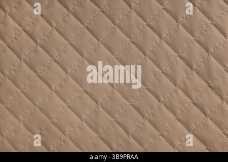 Checkered, diamond stitching pattern, brown quilted fabric background. Blanket or puffer jacket, stitch rhombus texture close up, macro. Wallpaper, ba Stock Photo