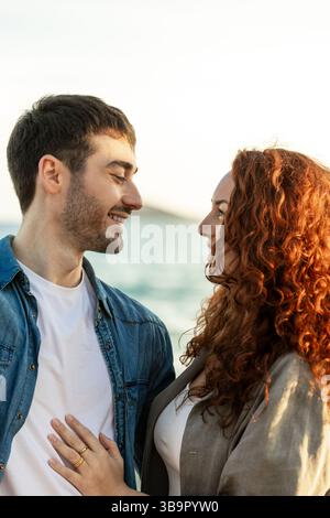 Romantic moment of a couple gazing into each other s eyes near the ocean, captured with warm lighting and soft focus on expressions and gentle contact Stock Photo