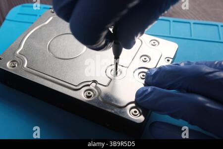 serviceman disassembling hard data disk drive to repair in service center Stock Photo