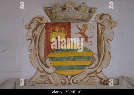 Painted heraldic coat of arms with crown and ornate frame on a historic wall in Seville, Spain, showing traditional Spanish heritage decoration. Stock Photo
