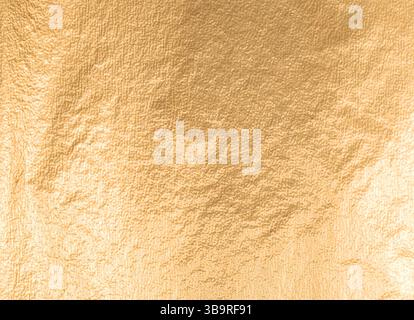 Gold metallic foil background with a soft, smooth texture. Elegant design in warm yellow tones, featuring a shimmering glow and refined matte finish. Stock Photo
