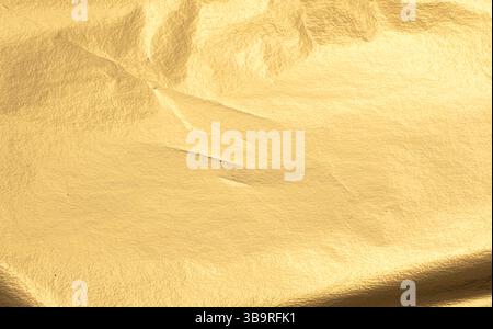 Gold metallic foil texture with a smooth, creased surface. Shiny, reflective material in warm yellow tones, featuring a subtle shimmer and gloss. Eleg Stock Photo