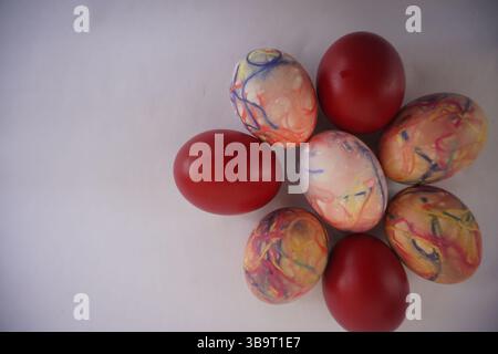 Red Easter eggs and colorful eggs dyed with thread dipped in various colors form a spring flower Stock Photo