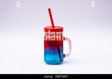 Two vibrant mason jars in red and blue colors, designed for serving juice or cold beverages, isolated on a clean white background. Ideal for summer dr Stock Photo