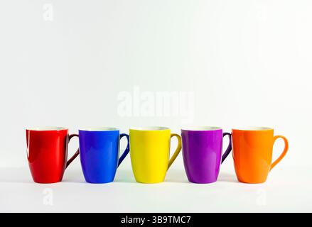 Vibrant coffee mugs stacked on a White minimalistic surface. Fun and Playful Color Cup Arrangement for Modern Product Display On white Background Stock Photo
