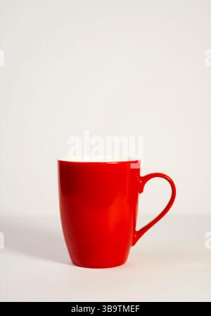 A vibrant red ceramic mug stands alone against a clean white backdrop. Stock Photo