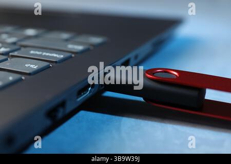 Usb flash drive connected to laptop on blue table, closeup Stock Photo