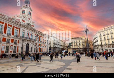 Tourists People Walking at Famous Puerta Del Sol (Gate of the Sun) Urban City Square. Famous Bell Clock Tower Dramatic Sunset Skyline Madrid Spain Stock Photo
