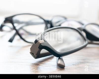 A variety of eyeglasses are displayed on a wooden table. The bright natural light highlights the different styles and frames, creating an inviting atm Stock Photo