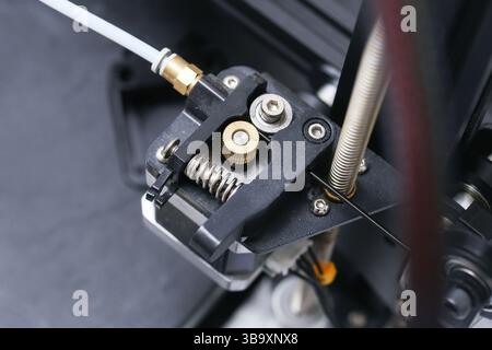 3D printer extruder closeup. Stepper motor with gear. Filament feed mechanism detail. Precision engineering component. Technical part of machine. Stock Photo