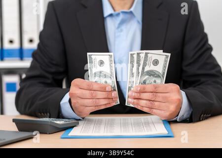 Business man, calculator and money in business finance for budget, costs or expenses at the office desk. Hands of male accountant counting and calcula Stock Photo