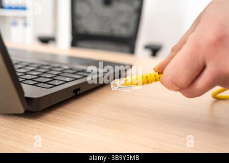 Close up of woman hands plugging ethernet cable on laptop on a desktop Stock Photo
