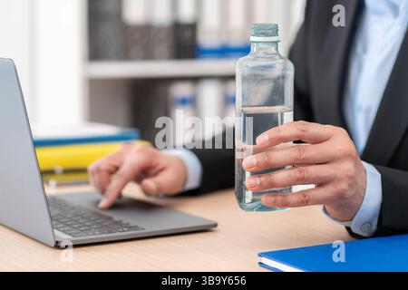 Close up of business man hands holding bottled water on a desk at the office Stock Photo