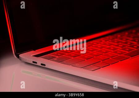 Close up of side view laptop keyboard with red light and dark background, in concept of infection or virus Stock Photo