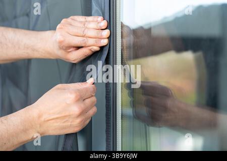 Hand hold pleated mosquito net wire screen handle on house window with copy space. Stock Photo