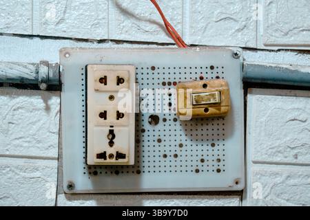 Old electrical switchboard mounted on a tiled wall Stock Photo