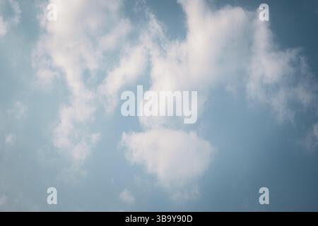 Fluffy white clouds floating in a bright blue sky Stock Photo
