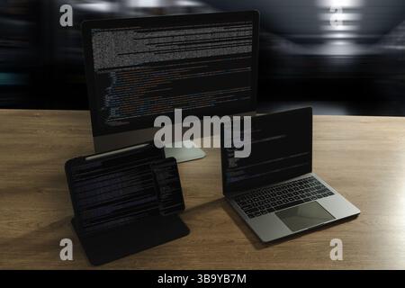 Programming workspace with code on desktop, laptop, tablet, and smartphone. Modern coding, software development, technology, IT office, web design, di Stock Photo