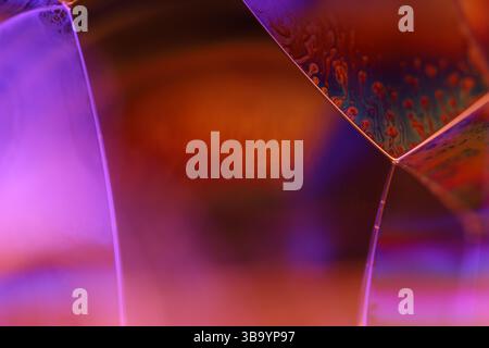 Green, orange and purple liquid reflections on dark background, bright liquid surface Stock Photo