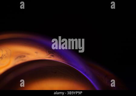 Green, orange and purple liquid reflections on dark background, bright liquid surface Stock Photo