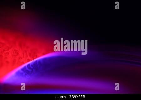 Red and purple fluid reflections on black background, liquid surface abstraction, colour edge, deep dark backgrounds, geometric water shapes Stock Photo
