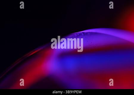 Red and purple fluid reflections on black background, liquid surface abstraction, colour edge, deep dark backgrounds, geometric water shapes Stock Photo