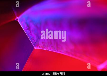 Red and purple fluid reflections on black background, liquid surface abstraction, colour edge, deep dark backgrounds, geometric water shapes Stock Photo