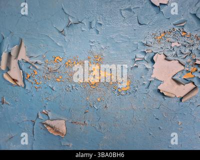 Close-up concrete wall with peeling blue paint revealing patches of yellow enamel underneath. Rough texture background aging, weathering and deteriora Stock Photo