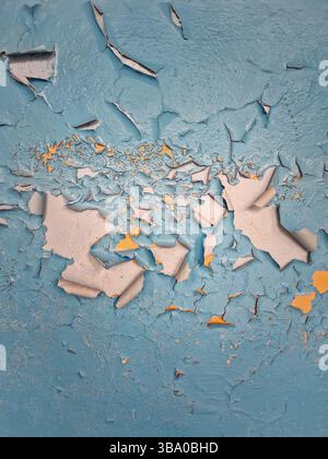 Close-up concrete wall with peeling blue paint revealing patches of yellow enamel underneath. Rough texture background aging, weathering and deteriora Stock Photo