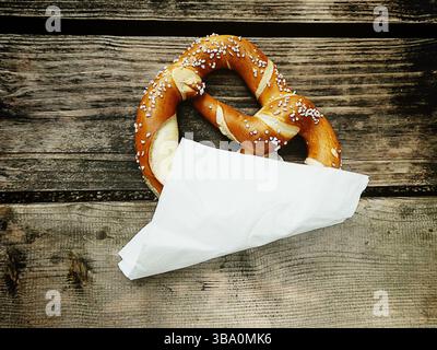 Pretzel bread typical Bavarian at beer garden on a grunge wooden bench Stock Photo